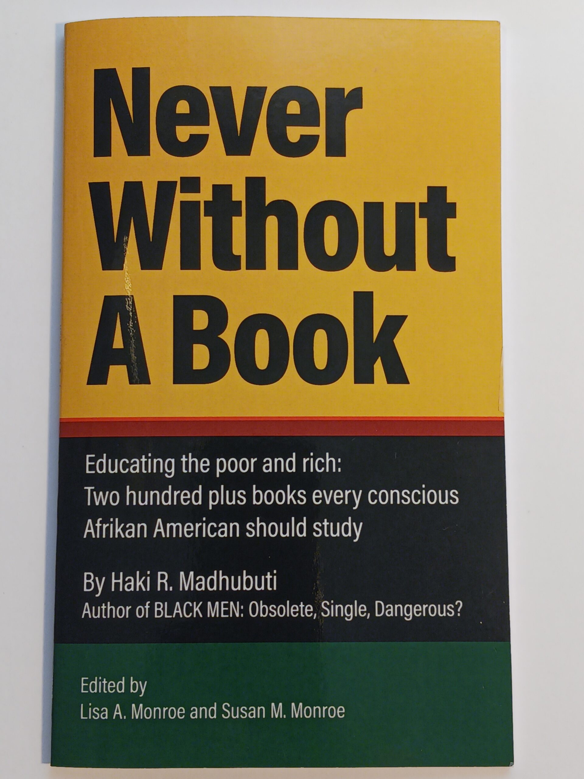 The image shows the cover of a book titled Never Without A Book by Haki R. Madhubuti, perfect for any book lover. The cover is yellow with black text and a green section at the bottom listing editors Lisa A. Monroe and Susan M. Monroe.