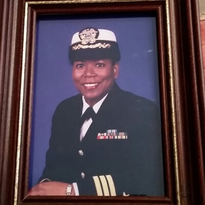 A framed portrait of a smiling woman in a formal navy uniform, adorned with medals, set against a blue background—celebrating veterans and their service with the Memphis Area Branch of ASALH at each monthly meeting. A framed portrait of a smiling woman in a formal navy uniform, adorned with medals, set against a blue background—celebrating veterans and their service with the Memphis Area Branch of ASALH at each monthly meeting.